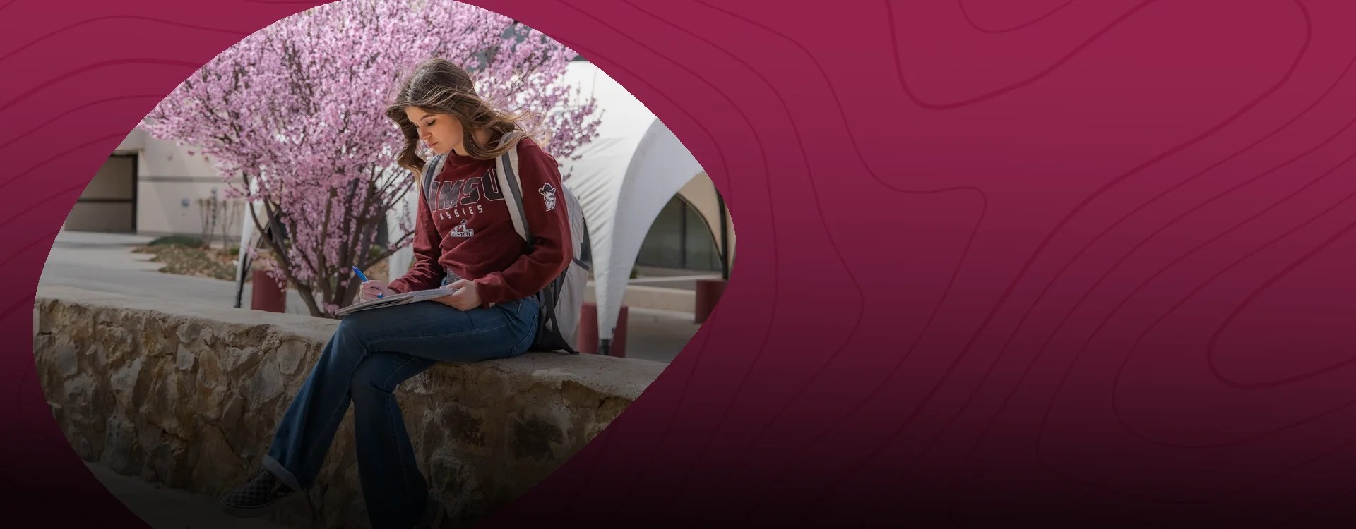A college student sits on a bench reading about psychology at New Mexico State University Global Campus